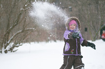 a girl child throwing a snowball 