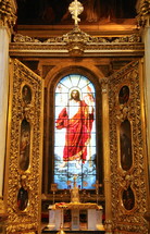 stained glass window of Christ behind an altar 