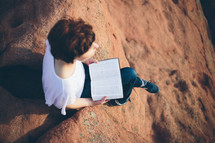 Woman sitting outside reading the Bible.