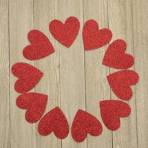 a circle of red hearts on a wood background for a Valentine's day frame
