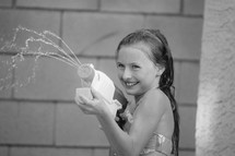 a little girl squirting a water gun 
