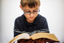 A boy looking down at an open Bible