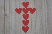 red hearts in the shape of a cross on a wood background 
