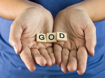 A young girl holds out the word "God"