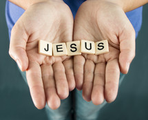 A girl holds out her hands with the word "JESUS"