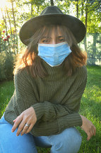 a young woman wearing a hat and a face mask 