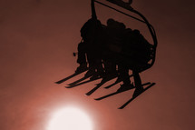 silhouette of skiers on a ski lift 