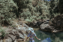 a woman in a dress walking by a pond 