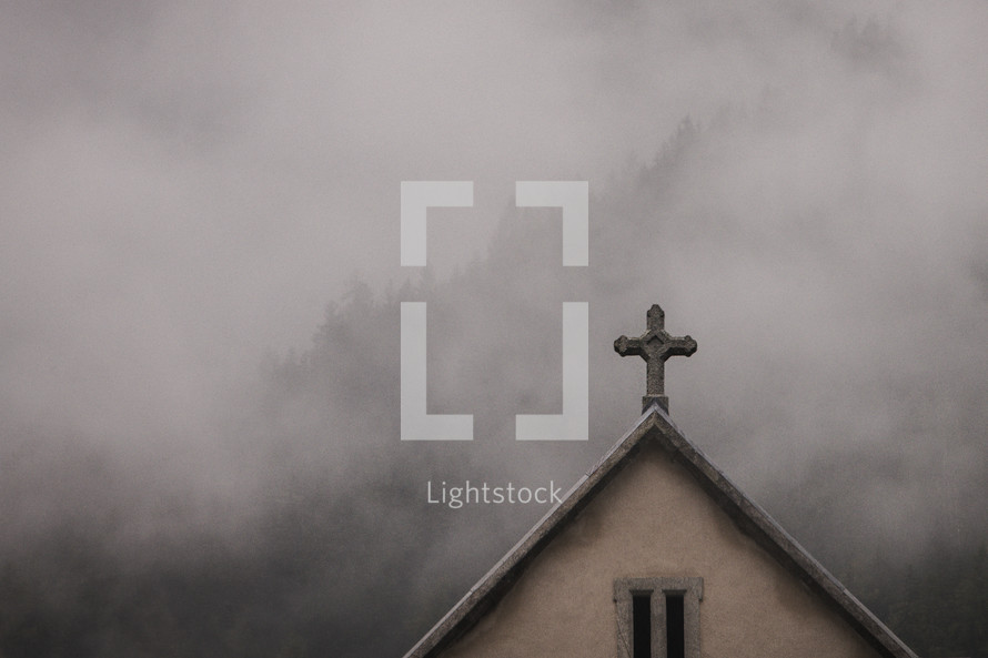 Small church with cross in the fog