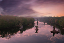 bridge over a still river at sunrise 