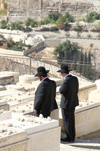 Jewish men leaving stones at a loved ones' grave on the Mount of Olives 
