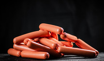 Delicious sausages boiled on the table. On a black background. High quality photo