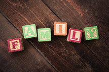"FAMILY" spelled out with colorful wooden children's blocks on a wooden surface.