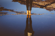 woman in boots standing in a puddle 