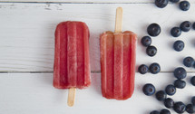 Frozen Homeamde Blueberry Popsicles on a White Wood Table