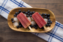Frozen Homeamde Blueberry Popsicles in a Wooden Bowl