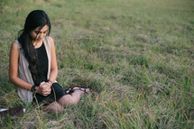 young woman praying in grass 