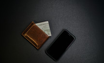 Brown leather wallet next to a cell phone.