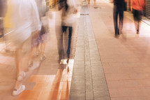 Blurry people busily walking along a sidewalk