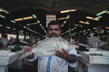 man holding a fish in a seafood market 