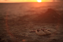 shoes in the sand on a beach at sunset 