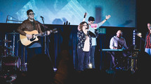 worship leaders performing on stage in front of a projection screen