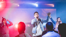 a man singing on stage during a worship service 