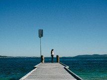 a woman standing on a dock looking out over the water 