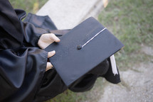 a graduate holding her graduation cap 