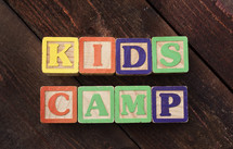 "Kids Camp" spelled out with colorful wooden children's blocks.