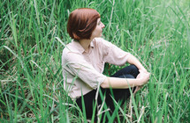a woman sitting in tall grasses 