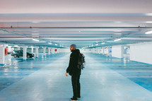 A man with a backpack standing in a parking garage 