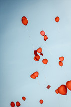 red heart shaped helium balloons in a blue sky