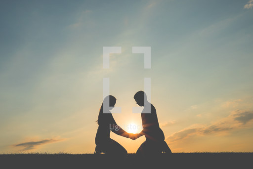 A couple holding hands kneeling in prayer — Photo — Lightstock