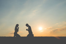 silhouettes of a couple kneeling in prayer together 