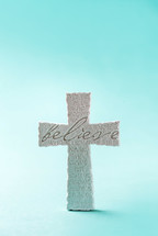 Stone cross with inscription Believe. Copy space. Christian backdrop. Biblical faith, gospel, salvation concept