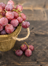 Rose grapes in wooden bucket on a woden tabl