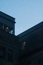 crescent moon over a city roof 