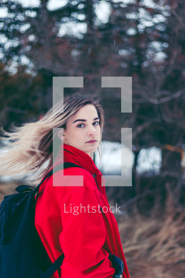 teen girl outdoors in a red coat and book bag 