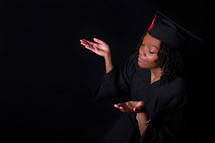 an African American woman graduate with raised hands 