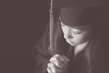 a graduate with praying hands 