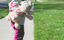a toddler carrying a stuffed animal 