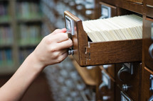Library card catalog cabinet with a hand opening drawer.