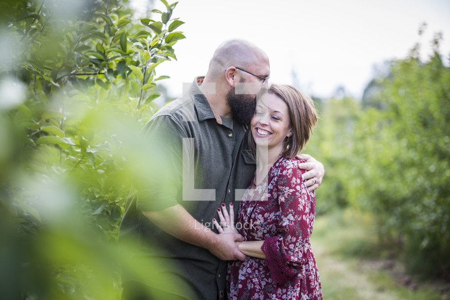 a couple hugging in an apple orchard 