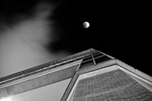looking up at a full moon above a building 