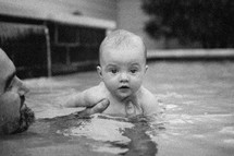 a father and infant son swimming in a pool 