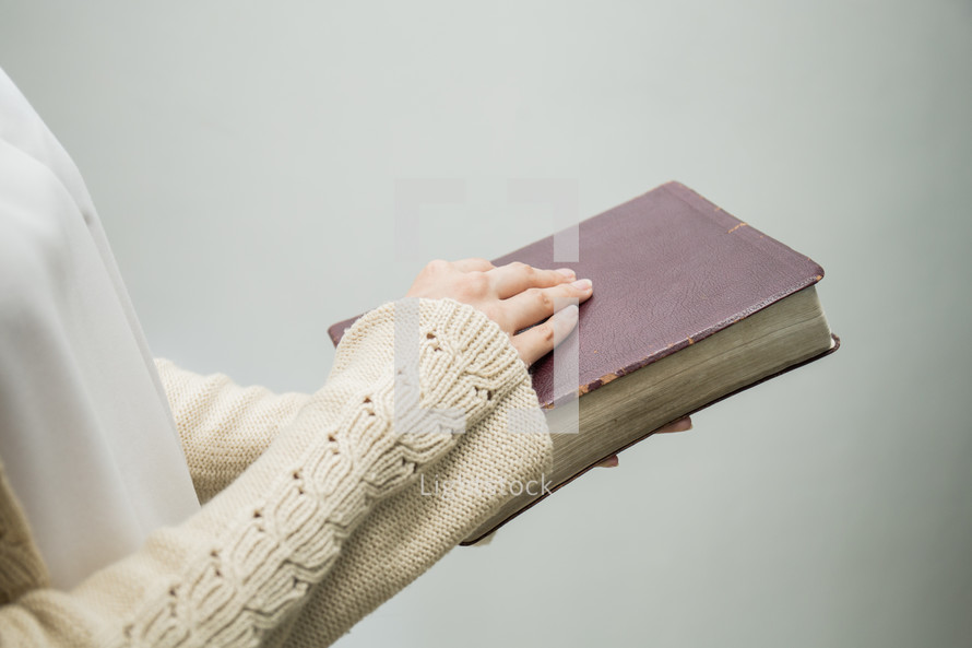 a woman standing holding a Bible 