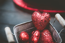 red sparkly hearts in a bucket 