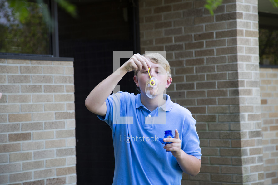 teen boy blowing bubbles 