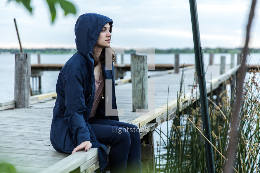 young woman in a hoodie sitting on a railing 